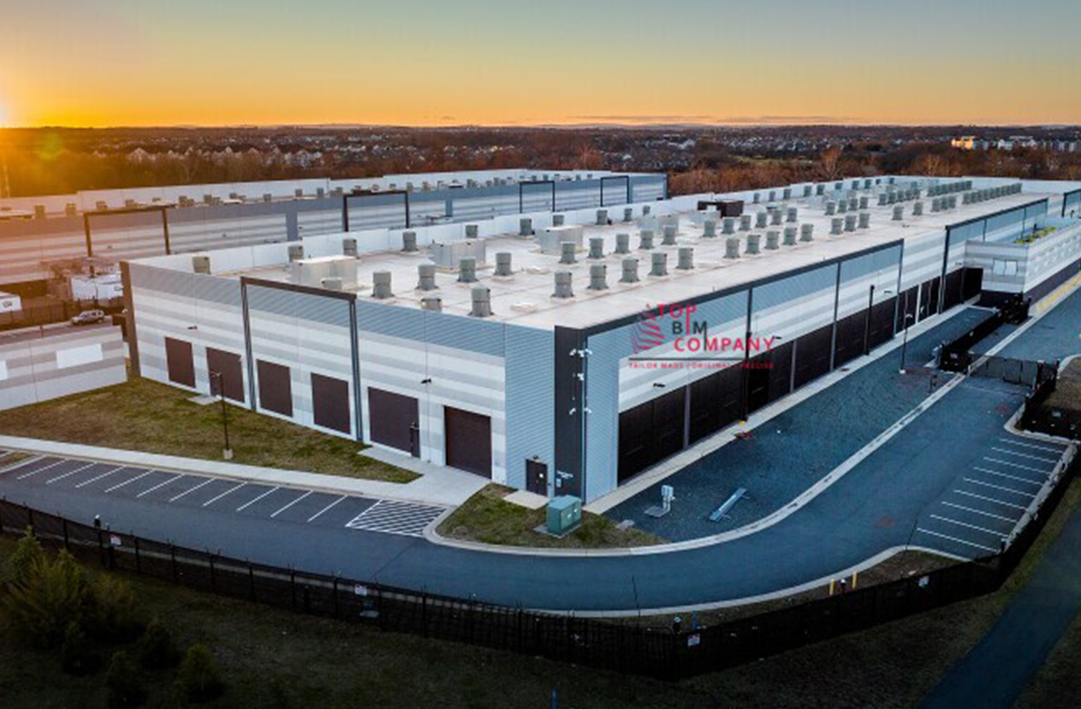 BIM Utility Modeling and Coordination services Exterior view of a completed data center facility with rooftop equipment, parking space, and secured fencing, captured during sunset